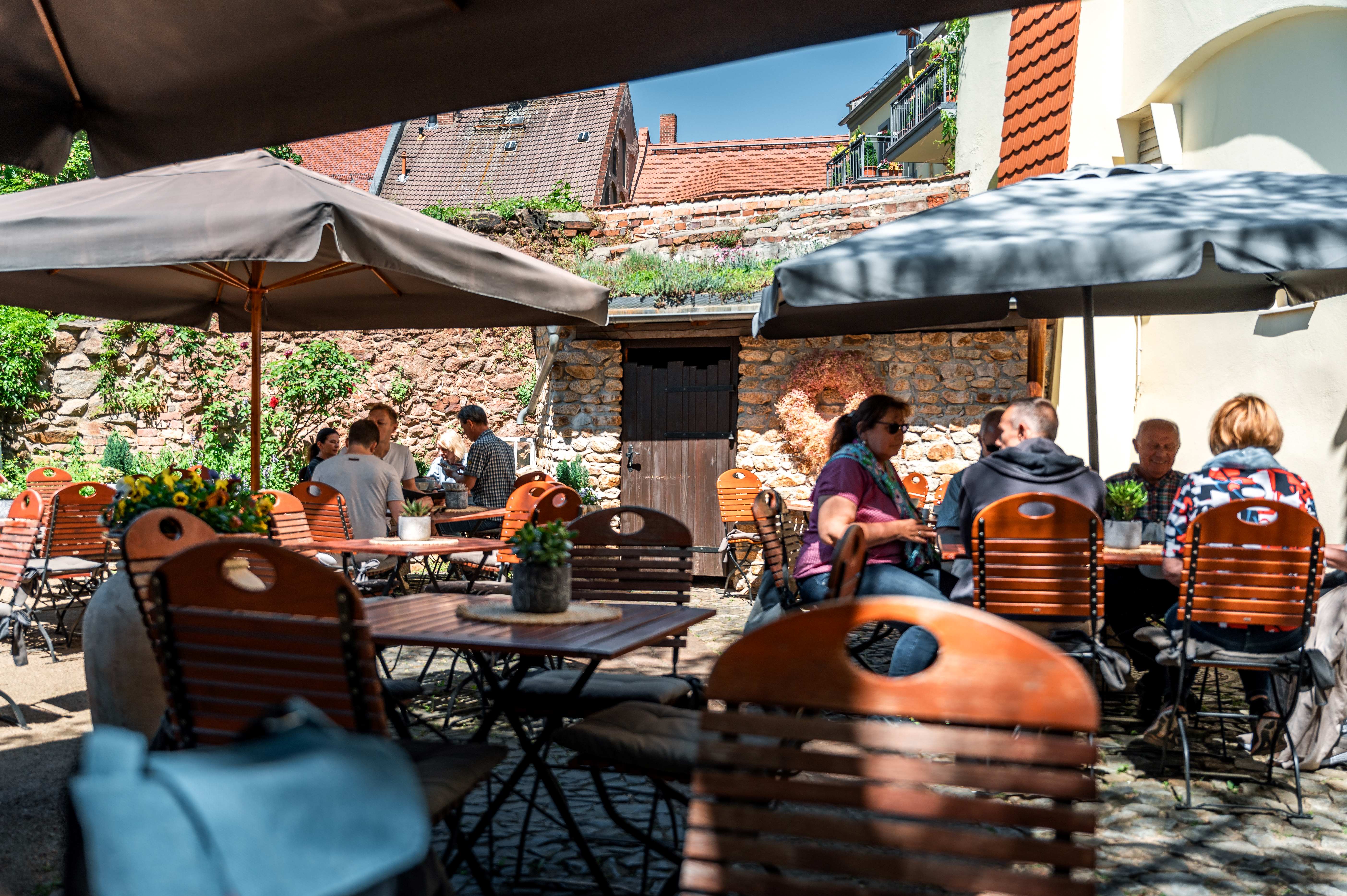 Menschen sitzen bei schönem Wetter im Außenbereich eines Cafés